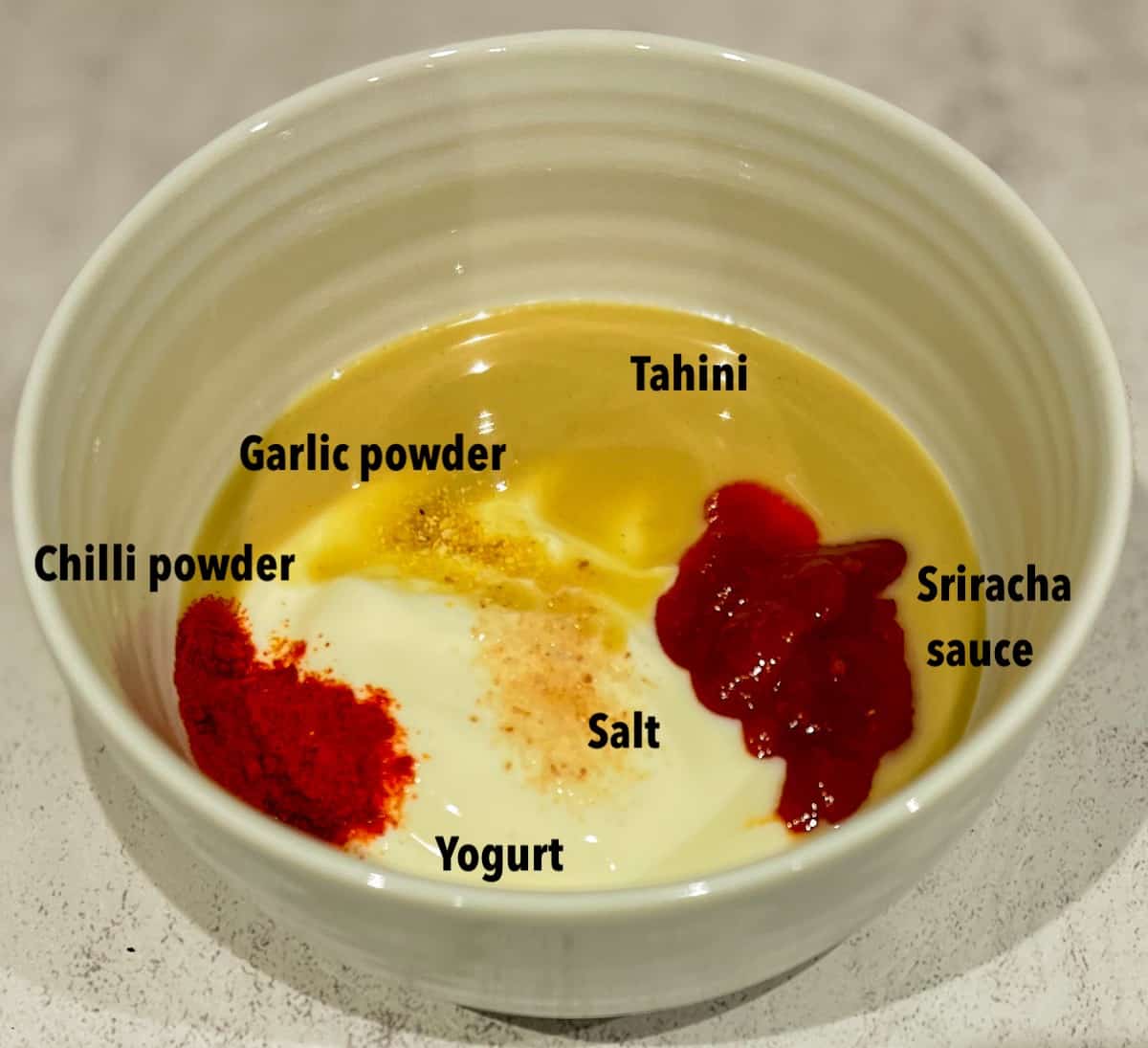 Yogurt, tahini, sriracha sauce, salt, garlic powder, salt and chilli powder in a bowl to make boom boom sauce.