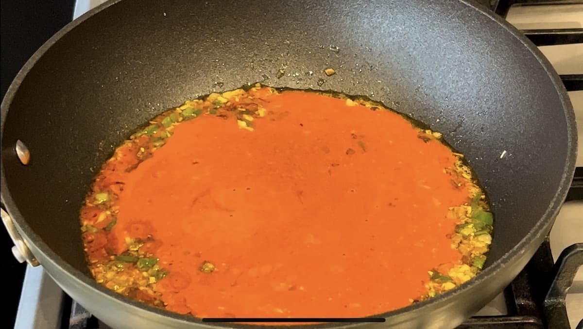 Gochujang pasta sauce cooking with shallots, garlic and green chillies